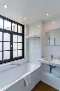 Baño blanco con bañera y lavamanos en Hotel Villa Monte, en Heist-op-den-Berg