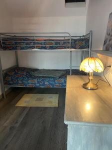 a room with a bunk bed with a desk and a lamp at Gîte en Baie de Somme in Saint-Blimont