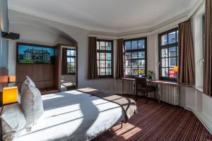 a bedroom with a bed and a desk and windows at Hotel Villa Monte in Heist-op-den-Berg