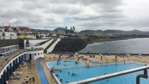 a group of people in a swimming pool next to a beach at By the Sea Azores in Ribeira Grande