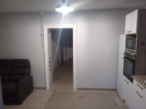 a living room with a black couch and a hallway at Le puits de Mine d'appart in Cransac