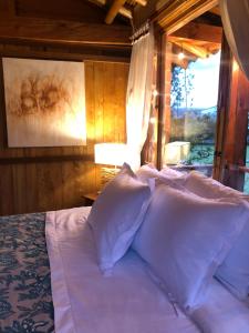 Un dormitorio con una cama con almohadas blancas y una ventana en Cozy Log Cabin-Ojo de Agua-Villa de Leyva-WIFI, en Villa de Leyva