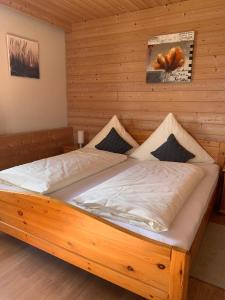 a bed in a room with a wooden wall at Pension Elisa in Lechbruck