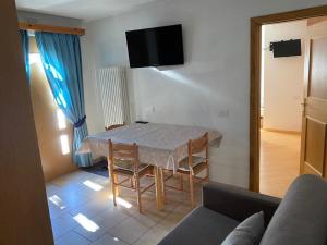 een woonkamer met een tafel, stoelen en een televisie bij Appartamento Piz Orsera in Livigno +7 foto's