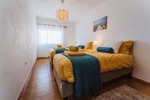 a bedroom with two beds with yellow and blue sheets at Mar do Pisão - Apartamento 2 quartos e vista mar in Santa Cruz