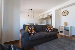 un soggiorno con divano blu e orologio di Mar do Pisão - Apartamento 2 quartos e vista mar a Santa Cruz