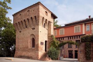un grand bâtiment en briques avec une tour dans une rue dans l'établissement Hotel Castello di Santa Vittoria, à Santa Vittoria dʼAlba