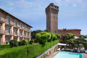 un edificio con una torre junto a una piscina en Hotel Castello di Santa Vittoria, en Santa Vittoria dʼAlba