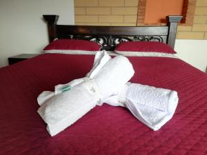 Una cama con camisas blancas y una pajarita. en Cabañas la villa, en Villa de Leyva