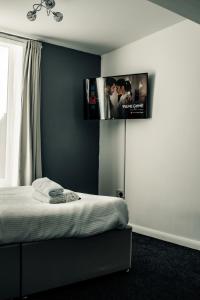 a bedroom with a bed with a tv on the wall at Dealhouse Apartments 10 in Huddersfield