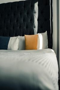 1 cama con cabecero negro y almohadas en Dealhouse Apartments 10, en Huddersfield