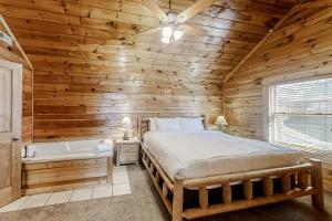 a log cabin bedroom with a bed and a bath tub at Parton Ways in Pigeon Forge