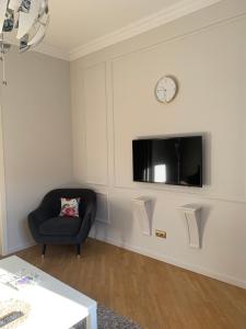 a living room with a chair and a clock on a wall at KAZA APART in Minsk