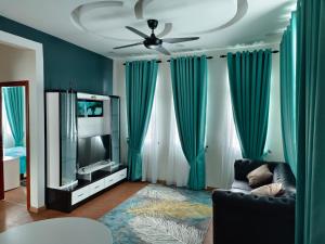 a living room with blue curtains and a couch and a television at LUXURY Modern House Kubang Kerian UNIFI 4 Bedrooms in Kota Bharu