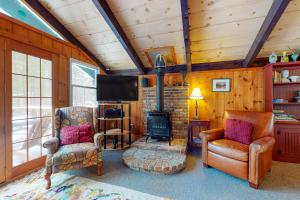 a living room with a fireplace and chairs and a television at 7 Merrimeeting Chalet in Conway
