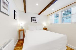 a white bedroom with a large bed and two windows at 7 Merrimeeting Chalet in Conway