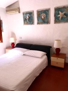 een slaapkamer met een bed met 2 lampen en schilderijen aan de muur bij L'Olivastro in Porto Cervo