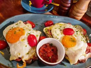 two fried eggs on a plate with a bowl of salsa at Salty Kisses and Sandy Toes in Firopótamos