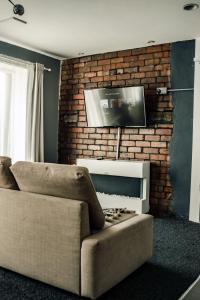 a living room with a couch and a tv on a brick wall at Dealhouse Apartments 10 in Huddersfield