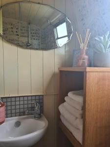 a bathroom with a sink and a mirror and towels at NEW 2022! Fixed stay characterful narrowboat at the Kelpies, Marigold Sunset in Falkirk