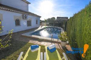 een achtertuin met een zwembad en twee stoelen en een huis bij Casa Amic in El Vendrell