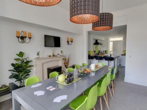 uma sala de jantar com uma mesa longa e cadeiras verdes em Sea-Esta em Weymouth