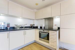 a kitchen with white cabinets and black counter tops at Modern 1 Bedroom Apartment Near Canary Wharf with Balcony in London