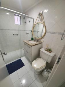 uma casa de banho com um WC, um chuveiro e um espelho. em Guarujá Flat no Guarujá