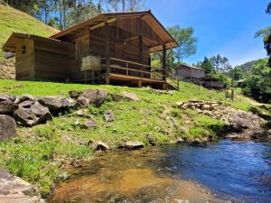 a log cabin with a river in front of it at Cabanas Pousada Esmeraldas in Annitapolis
