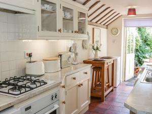 eine Küche mit weißen Schränken und einem Herd mit Backofen in der Unterkunft Garden Cottage in Ludlow