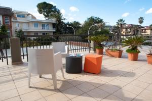 patio ze stołami, krzesłami i doniczkami w obiekcie Hostal Al Porto w mieście San Benedetto del Tronto