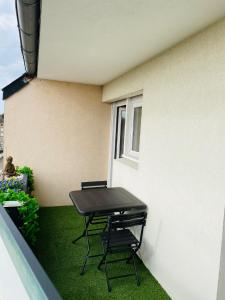 stół i krzesła siedzące na balkonie budynku w obiekcie Cocon déco + terrasse & parking fermé Zénith Ester w mieście Limoges