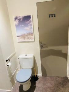 La salle de bains est pourvue de toilettes avec un siège bleu. dans l'établissement Cocon déco + terrasse & parking fermé Zénith Ester, à Limoges