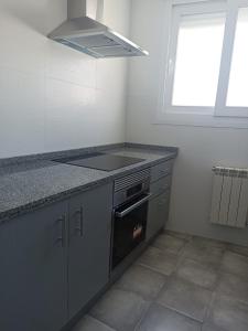 a kitchen with a stove and a sink and a window at Apartamento Barbadillo - Redmansur in Cáceres +22 photos