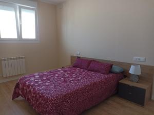 1 dormitorio con 1 cama con edredón morado y ventana en Apartamento Barbadillo - Redmansur, en Cáceres