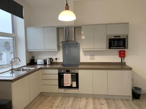 a kitchen with white cabinets and a sink at Piccadilly by Pureserviced in Plymouth