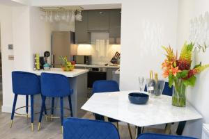 a kitchen with a white table and blue chairs at Outstanding modernised 3/4 double bedroomed house in Littlehampton