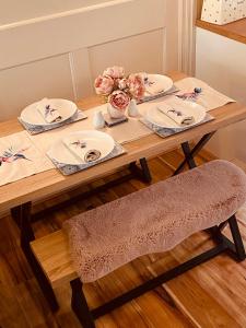 a wooden table with plates and flowers on it at Heptonstall Cottage, Heptonstall, Hebden Bridge in Heptonstall