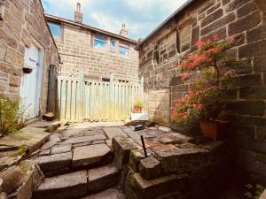 Heptonstall Cottage, Heptonstall, Hebden Bridge في Heptonstall: مبنى من الطوب مع سياج ونصب الفخار