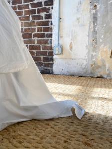 a wedding dress sitting on the floor next to a brick wall at The Grant by Black Swan in Savannah