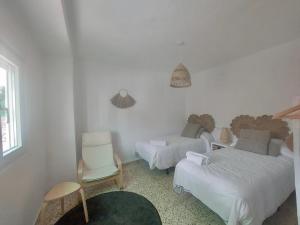 Biały pokój z 2 łóżkami i krzesłem w obiekcie La huerta del Castillo w mieście Castillo de Locubín