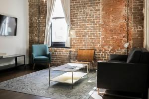 a living room with a couch and a table and a brick wall at The Grant by Black Swan in Savannah