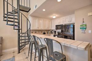a kitchen with a bar with chairs and a spiral staircase at Idyllic Montgomery Condo with Pool and Lake View! in Montgomery