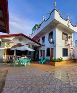ein Gebäude mit einer Terrasse mit Stühlen und einem Sonnenschirm in der Unterkunft Sealor Pension House in Puerto Princesa