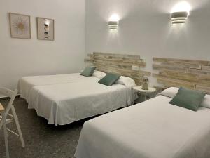a hotel room with two beds and two tables at Hostal Paco Marbella in Marbella