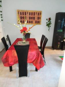 a red table with black chairs and a vase with flowers on it at Maison de 3 chambres a Saint Pierre a 300 m de la plage avec wifi in Saint-Pierre