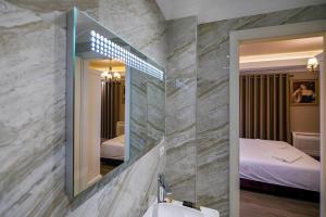 a bathroom with a mirror and a sink and a bed at Legacy Boutique Hotel in Korçë