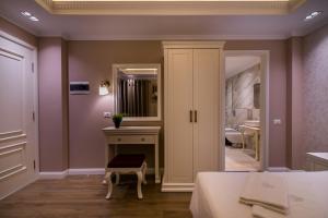 a bedroom with a bed and a vanity and a mirror at Legacy Boutique Hotel in Korçë