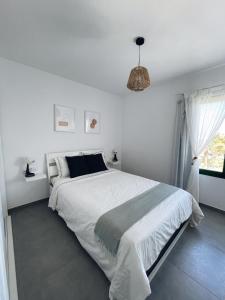 コスタ・テギセにあるApartamentos Catairaの白いベッドルーム(大型ベッド1台、窓付)