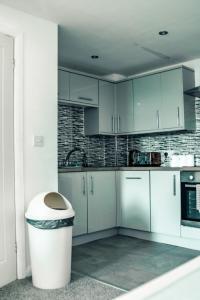 una cucina con armadi bianchi e un cestino di Apartments Dealhouse 4 a Huddersfield